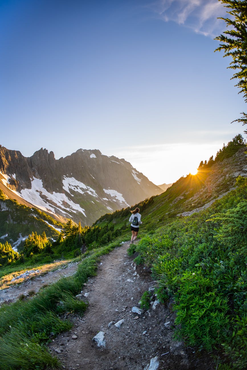 back view of a woman running up the mountain trail